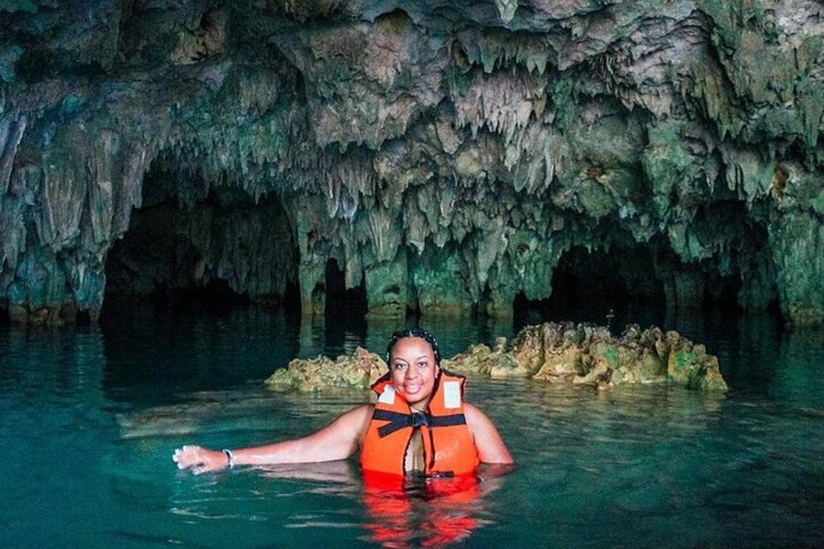 seorang lelaki di dalam air di hadapan sebuah gua