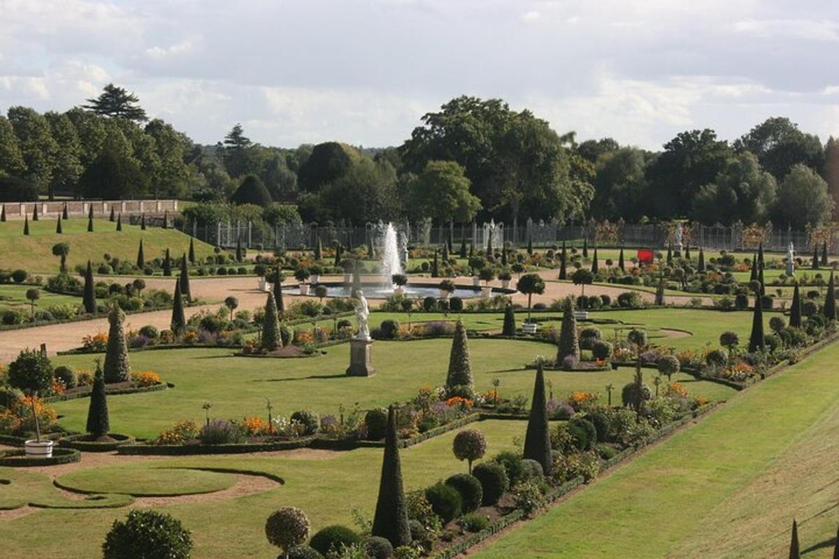 Un jardín con una fuente en medio de un parque.