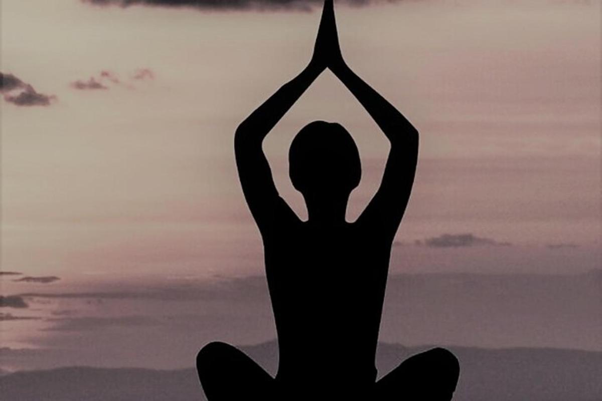 a woman doing a yoga pose in front of the sunset
