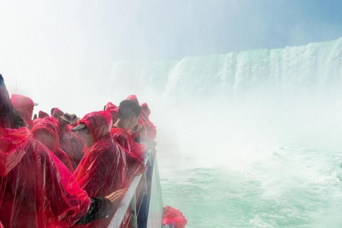Un grupo de personas con túnicas rojas en un bote frente a una cascada.