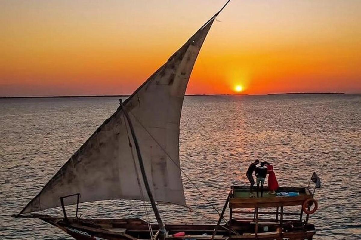 Una pareja en un velero en el agua al atardecer