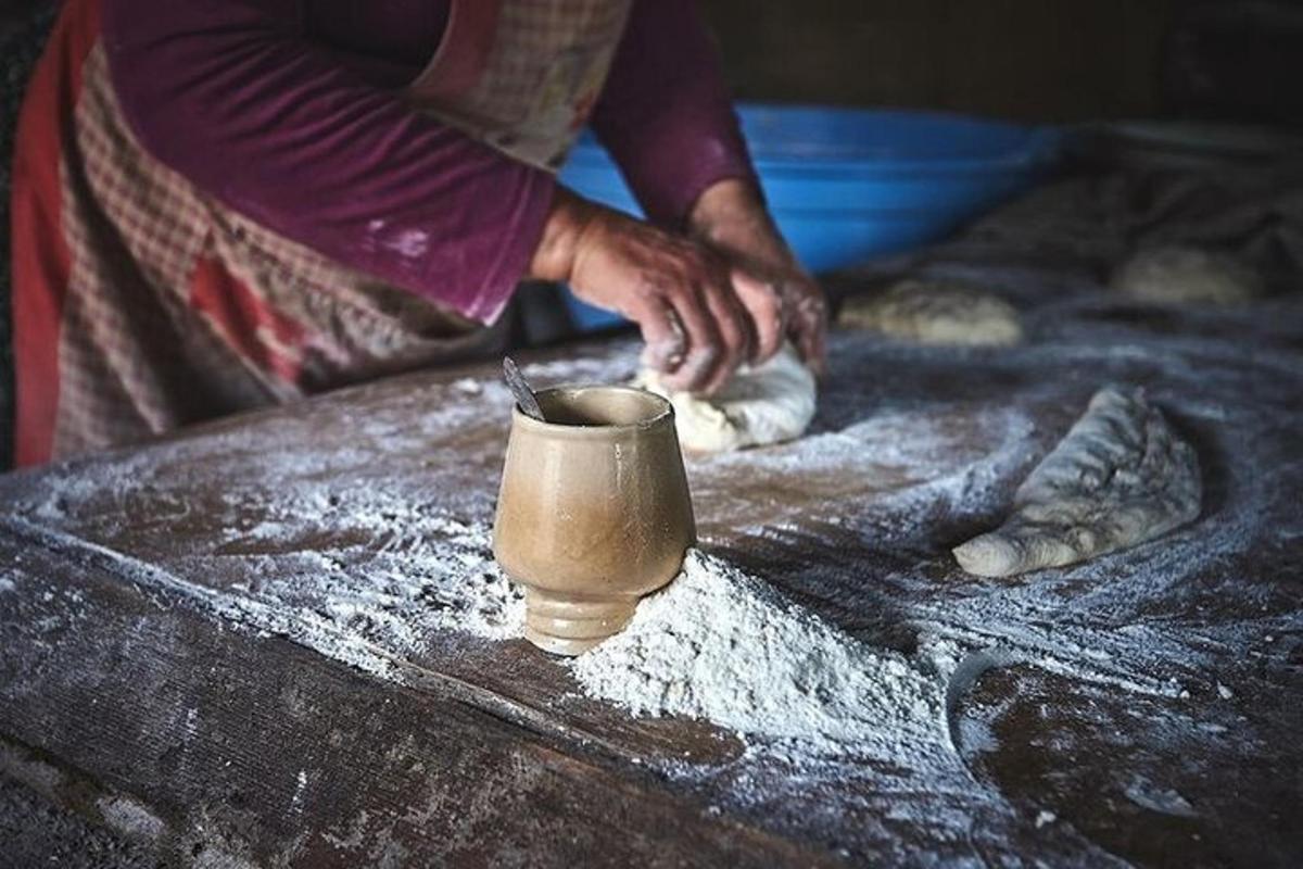 شخص يعجن الدقيق على طاولة باستخدام كوب
