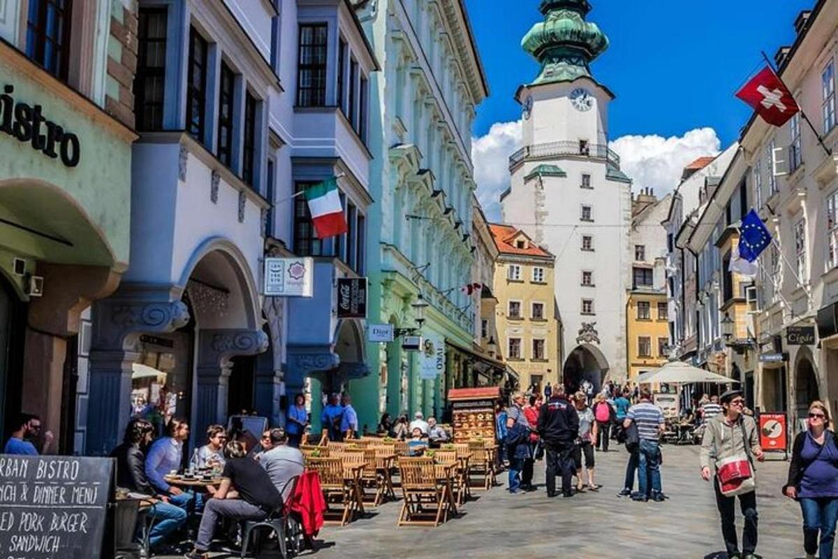 skupina lidí jdoucích po ulici s hodinovou věží