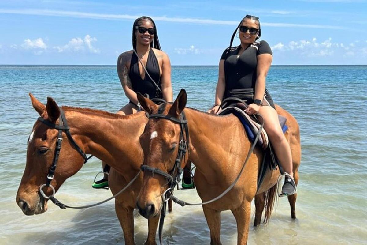 to kvinner rir på hester på stranden