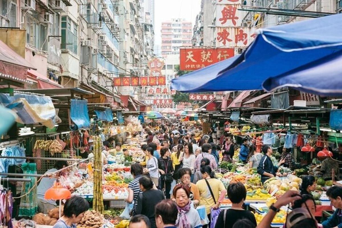 uma multidão de pessoas caminhando por um mercado com frutas e vegetais