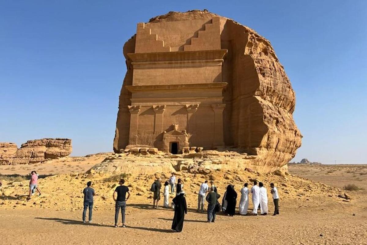 a group of people standing in front of a large rock