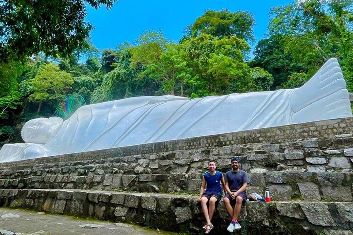 two people sitting on a stone wall in front of a whale statue
