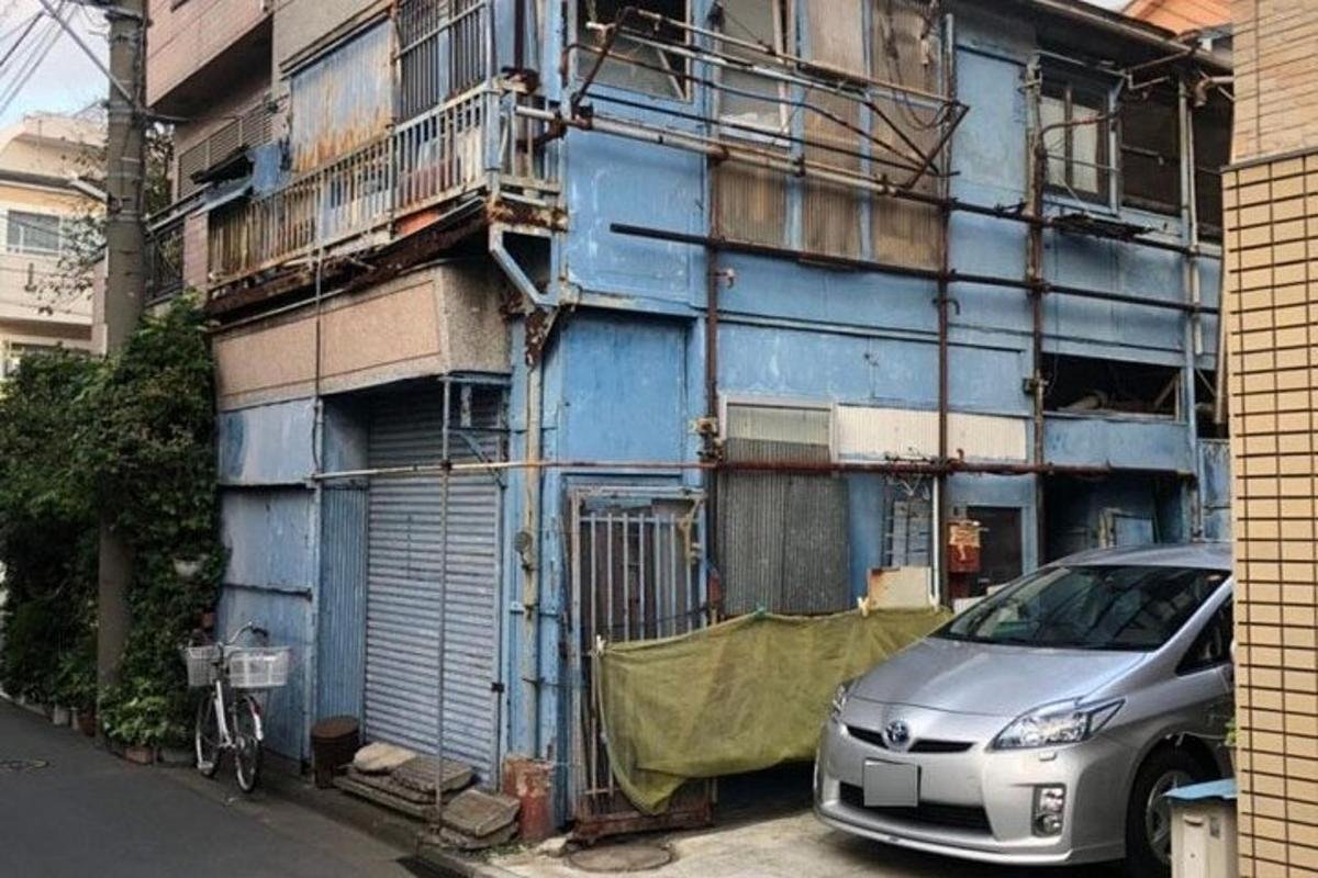un edifici blau amb un cotxe aparcat davant