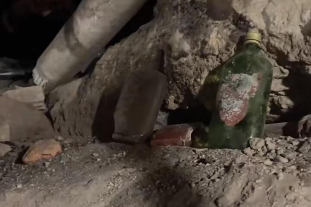 a green glass bottle sitting in a pile of rubble