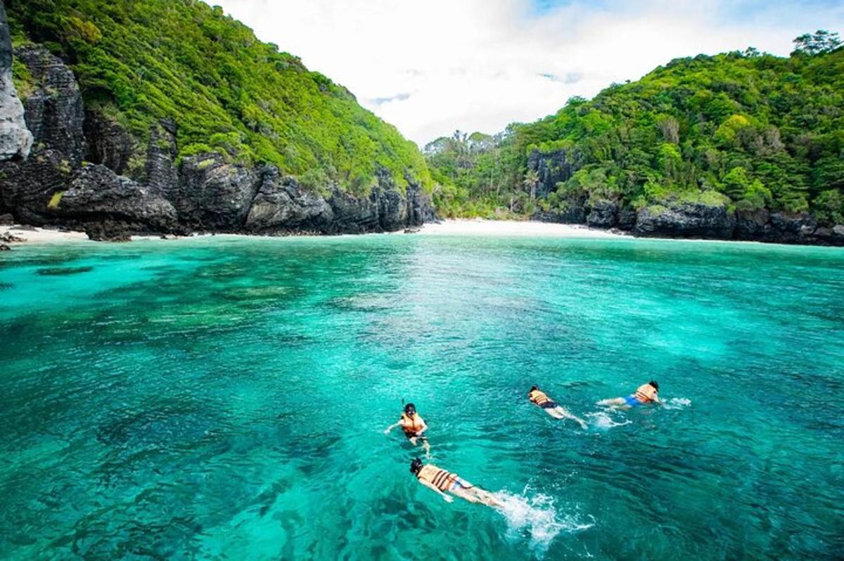 Tres personas nadando en el agua cerca de una playa