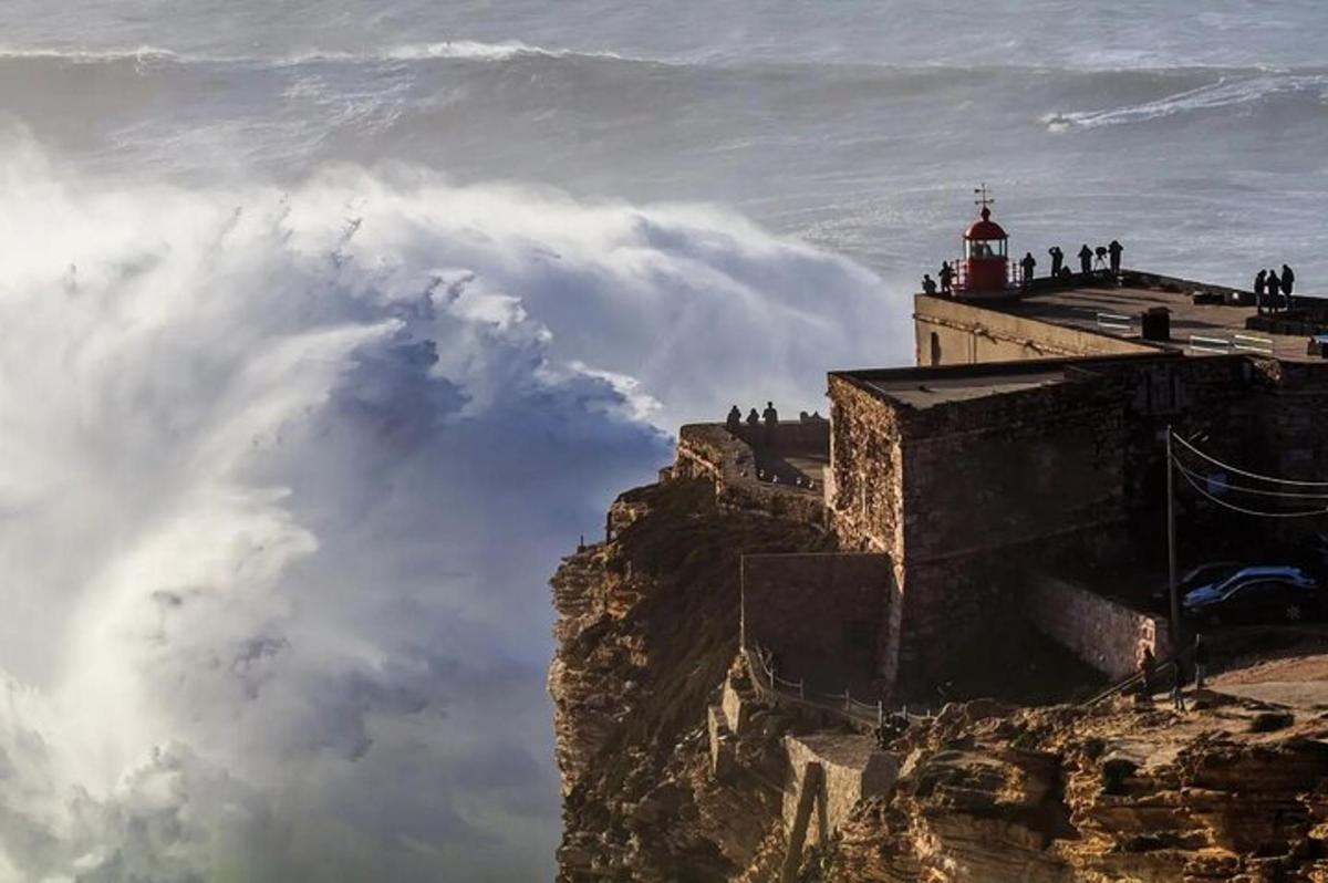 a lighthouse on the edge of a mountain with clouds