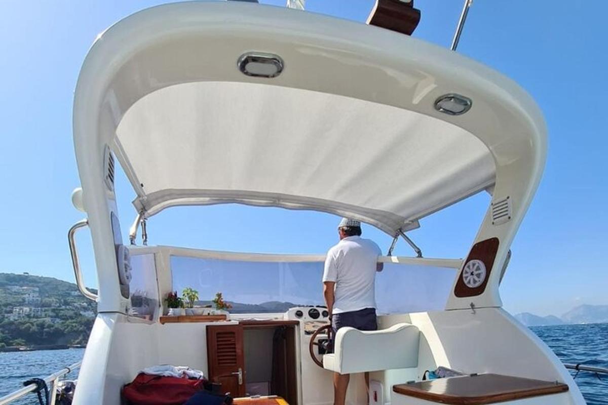 um homem em pé na parte de trás de um barco na água