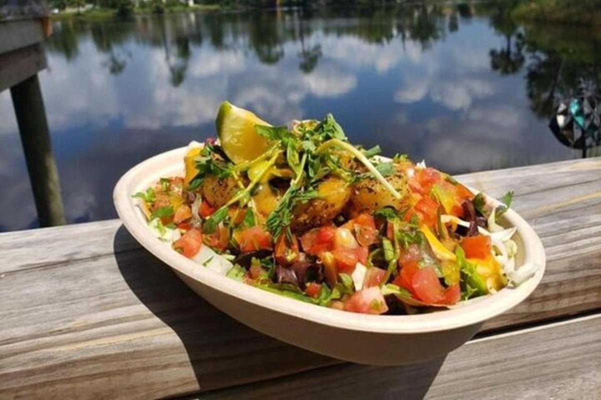 một đĩa salad trong bát trên bàn gần một vùng nước