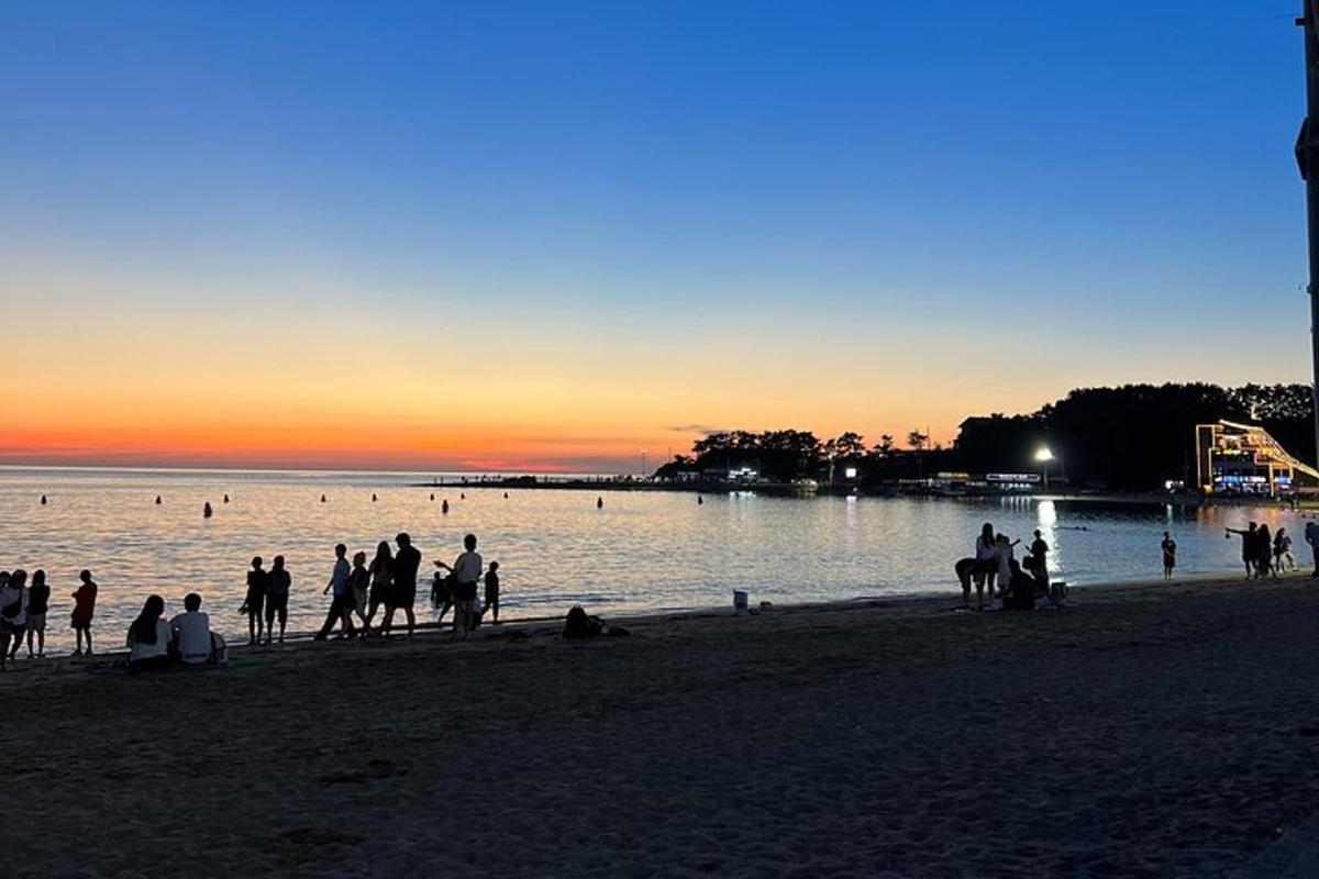 un groupe de personnes debout sur la plage au coucher du soleil