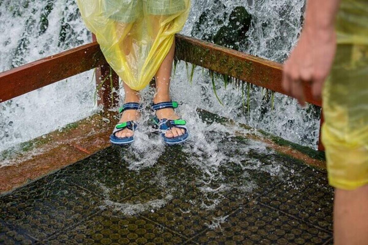 zwei Menschen in Sandalen stehen in einem Wasserfall
