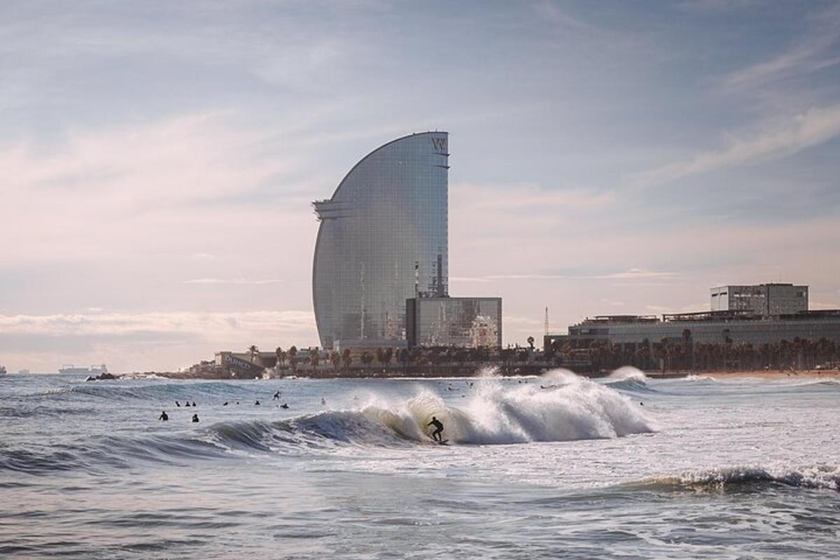 una persona che cavalca un'onda nell'oceano con un edificio sullo sfondo