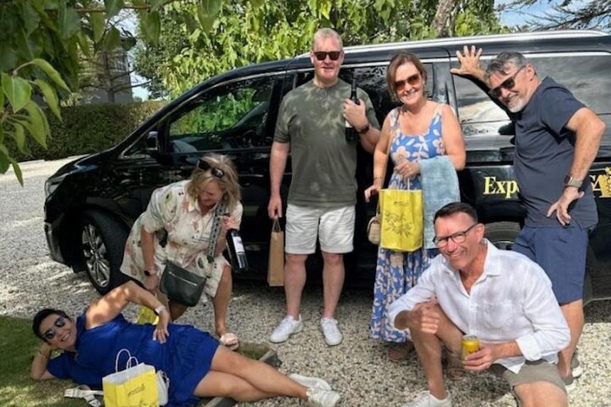 un grupo de personas de pie delante de un coche