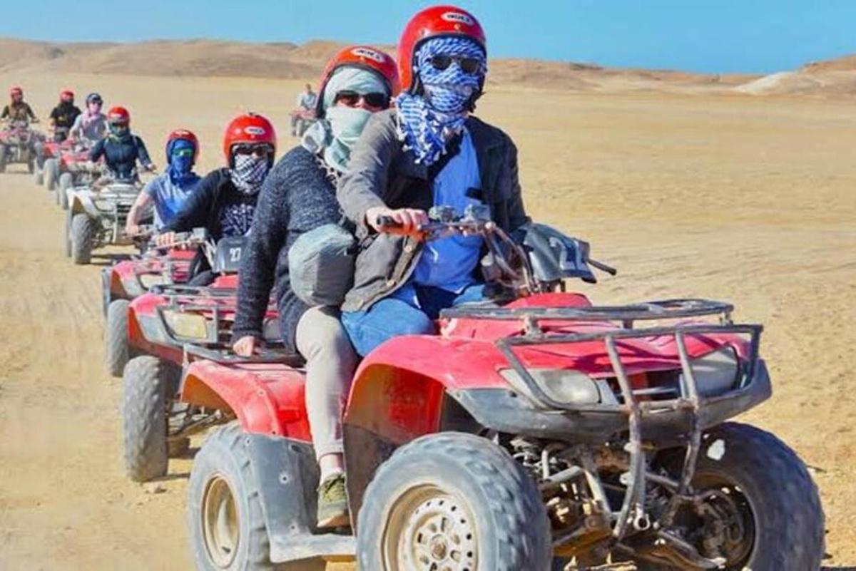un grup de persones conduint quads al desert