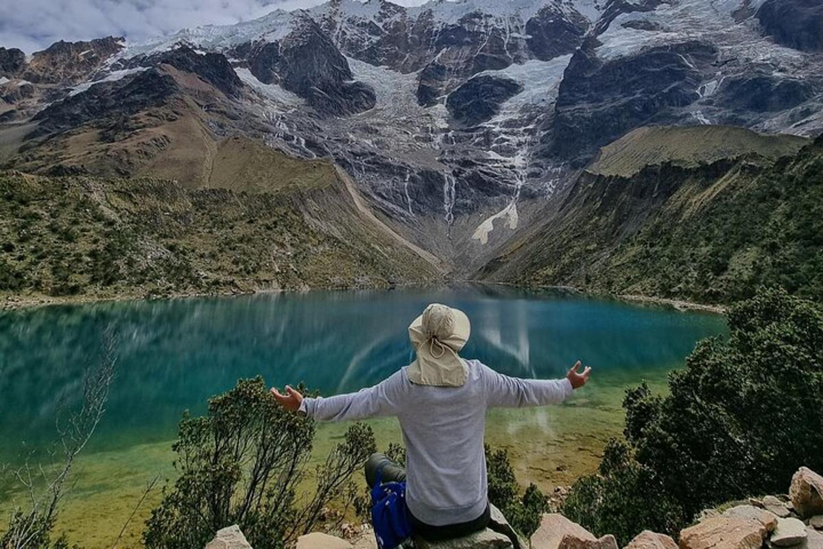 dua orang duduk di atas gunung yang menghadap ke tasik