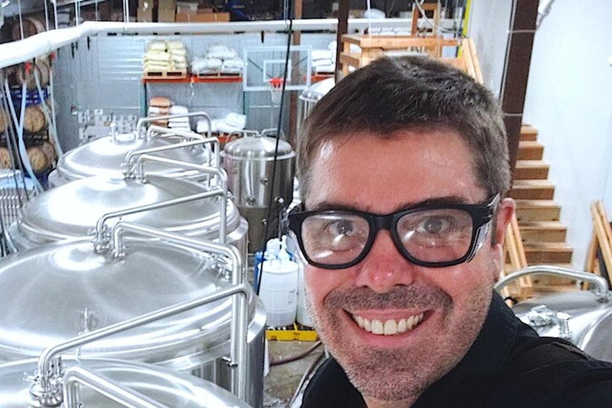 a man wearing glasses standing in front of sinks