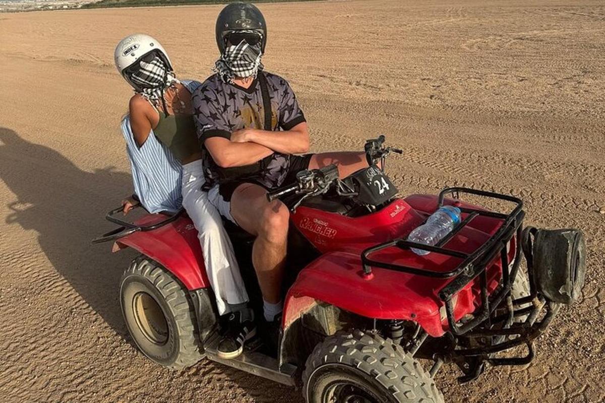a man and a woman riding on a four wheeler in the desert