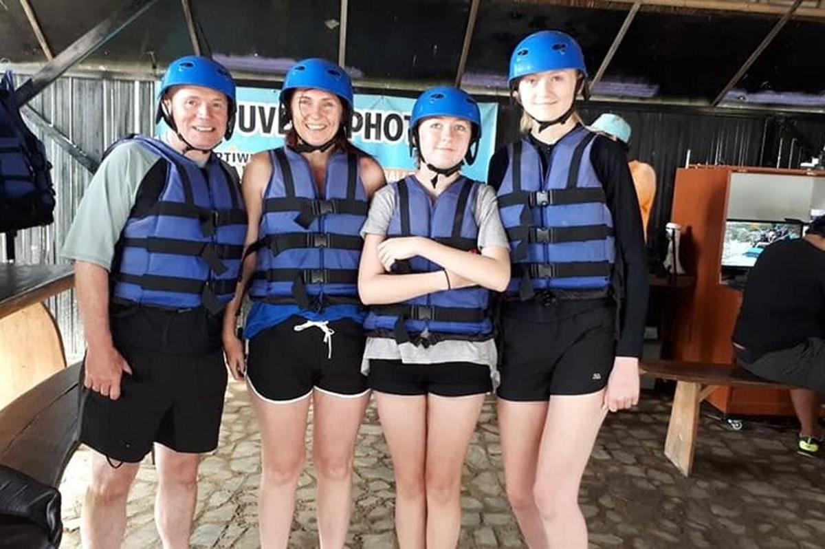 skupina lidí v helmách a záchranných vestách na raftu