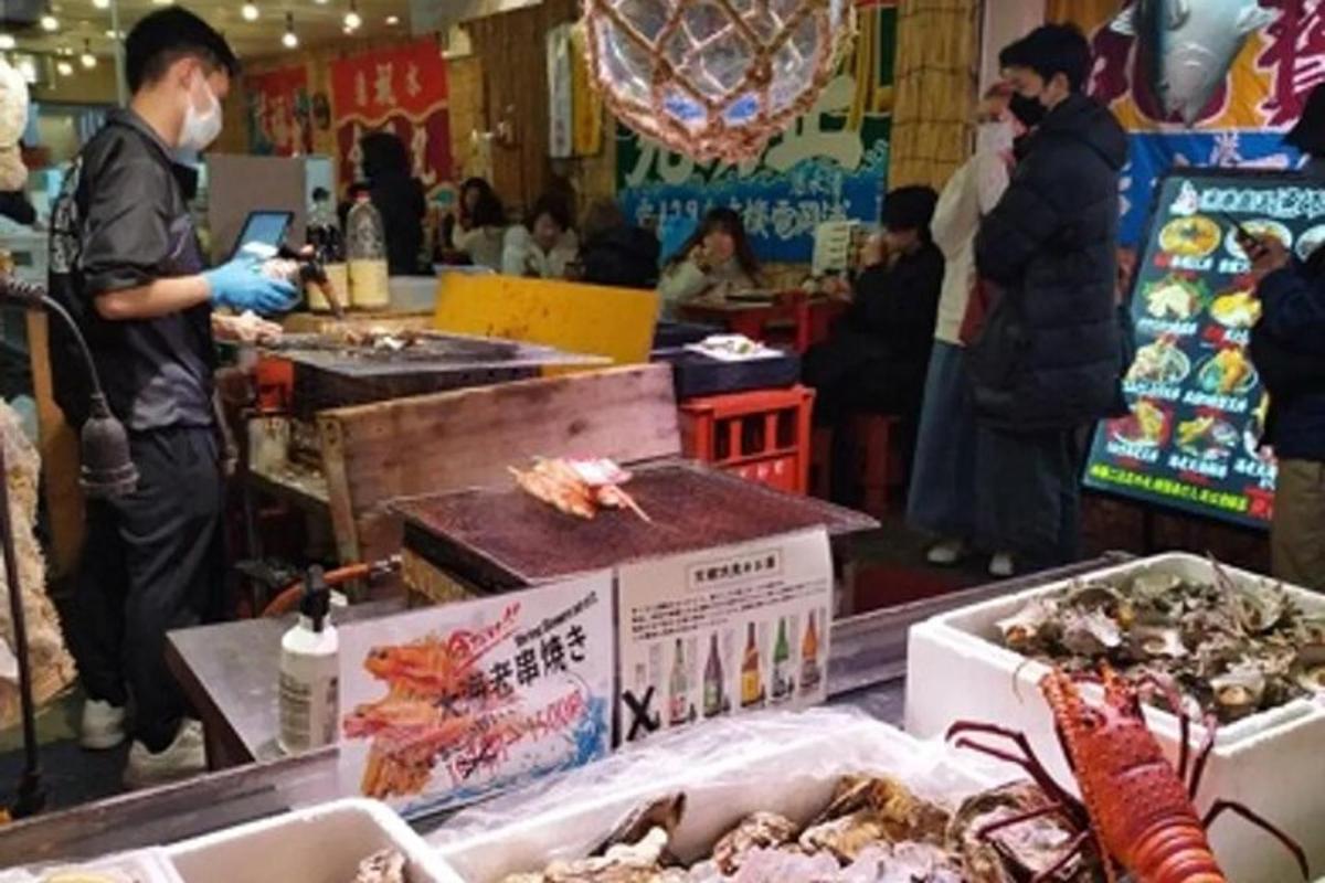 sekumpulan orang berdiri di pasar dengan makanan