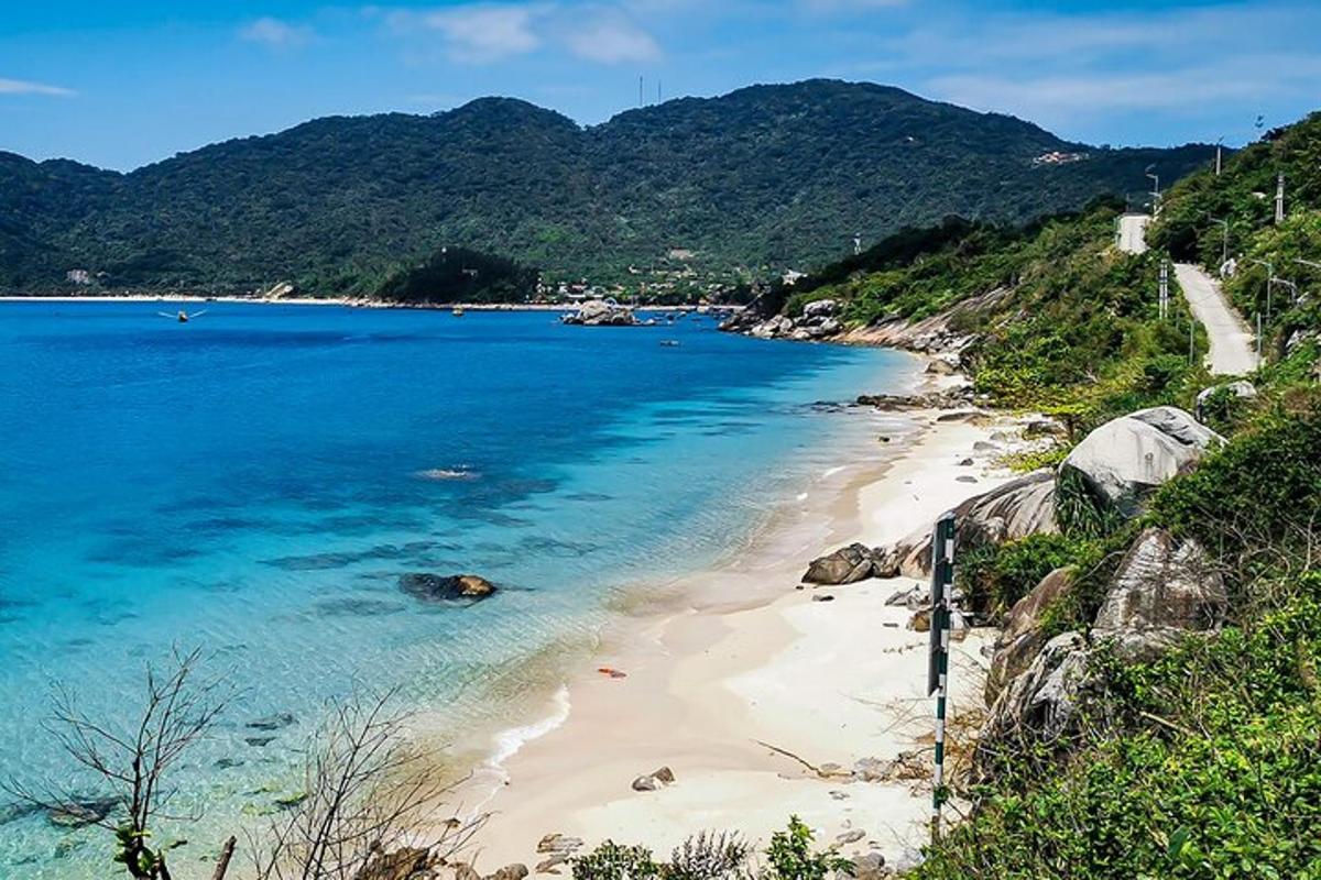uma praia com água azul e montanhas ao fundo