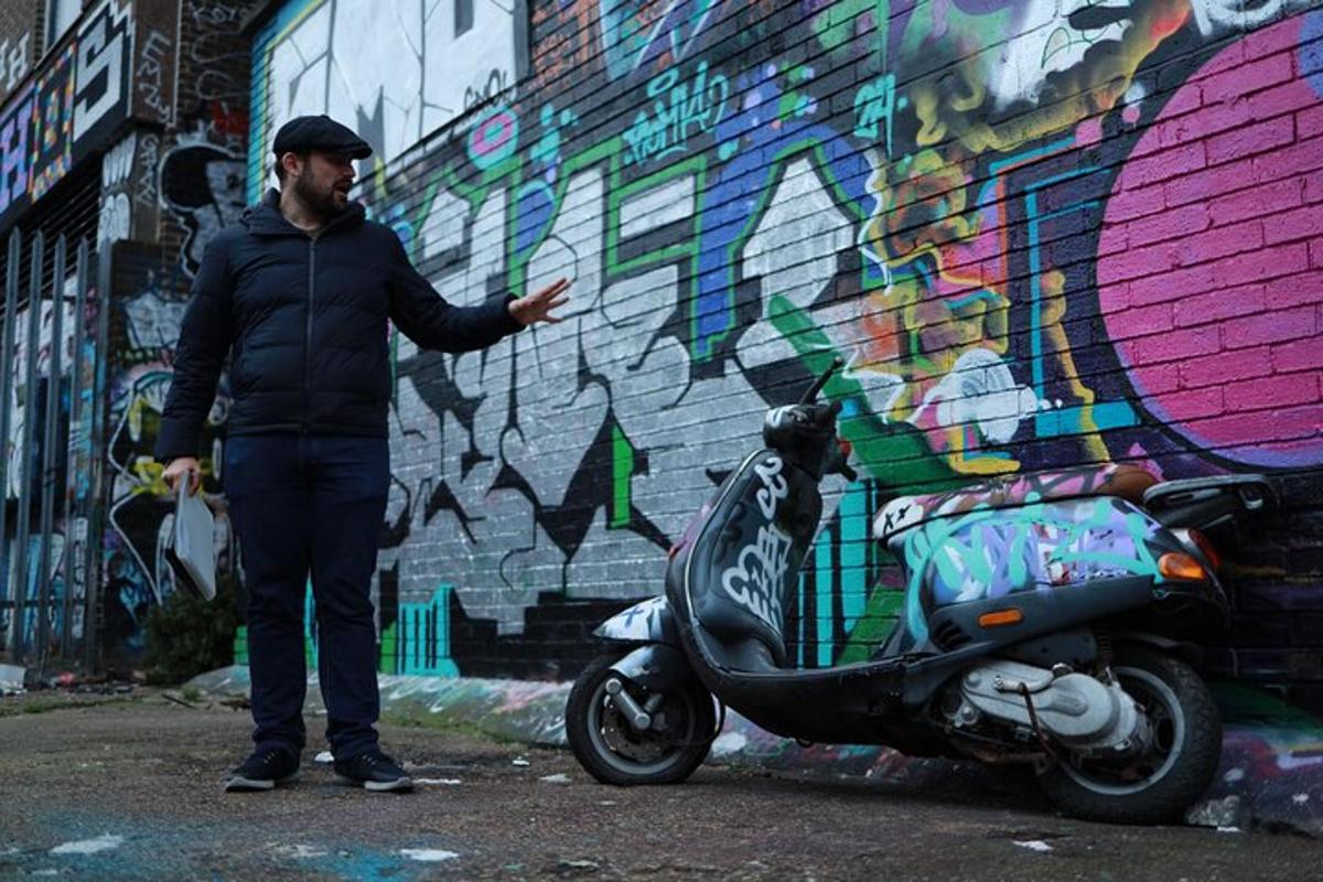 een man die naast een scooter voor een muur staat