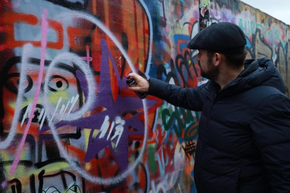 seorang pria sedang mengecat dinding dengan grafiti