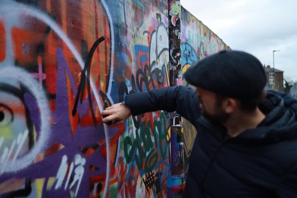 seorang pria sedang mengecat dinding dengan grafiti