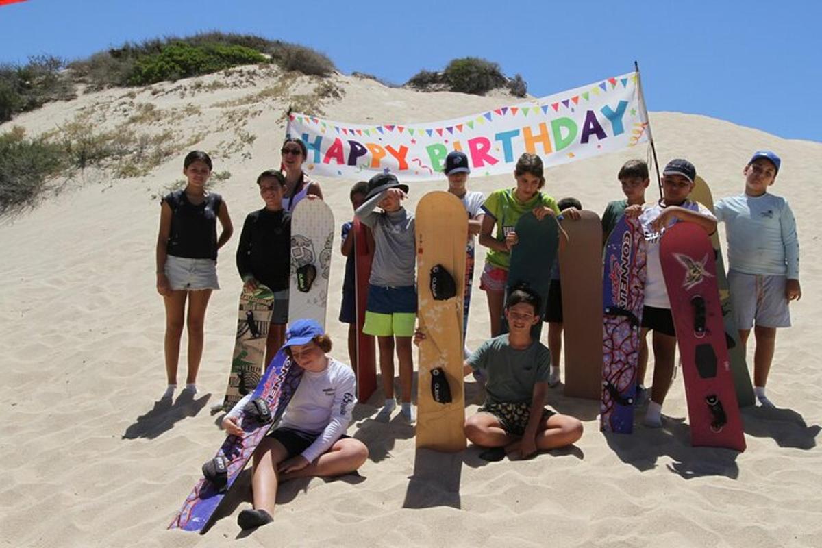 a group of young men standing in the sand with skateboards