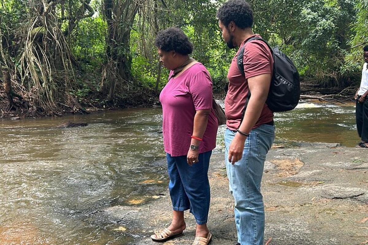 Dos personas paradas en un río mirando el agua.