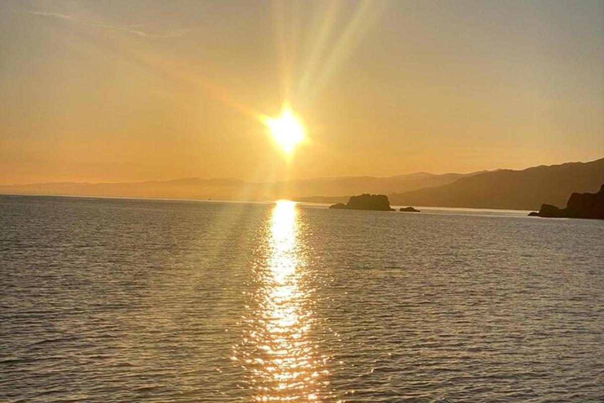 un tramonto su uno specchio d'acqua con il sole nel cielo