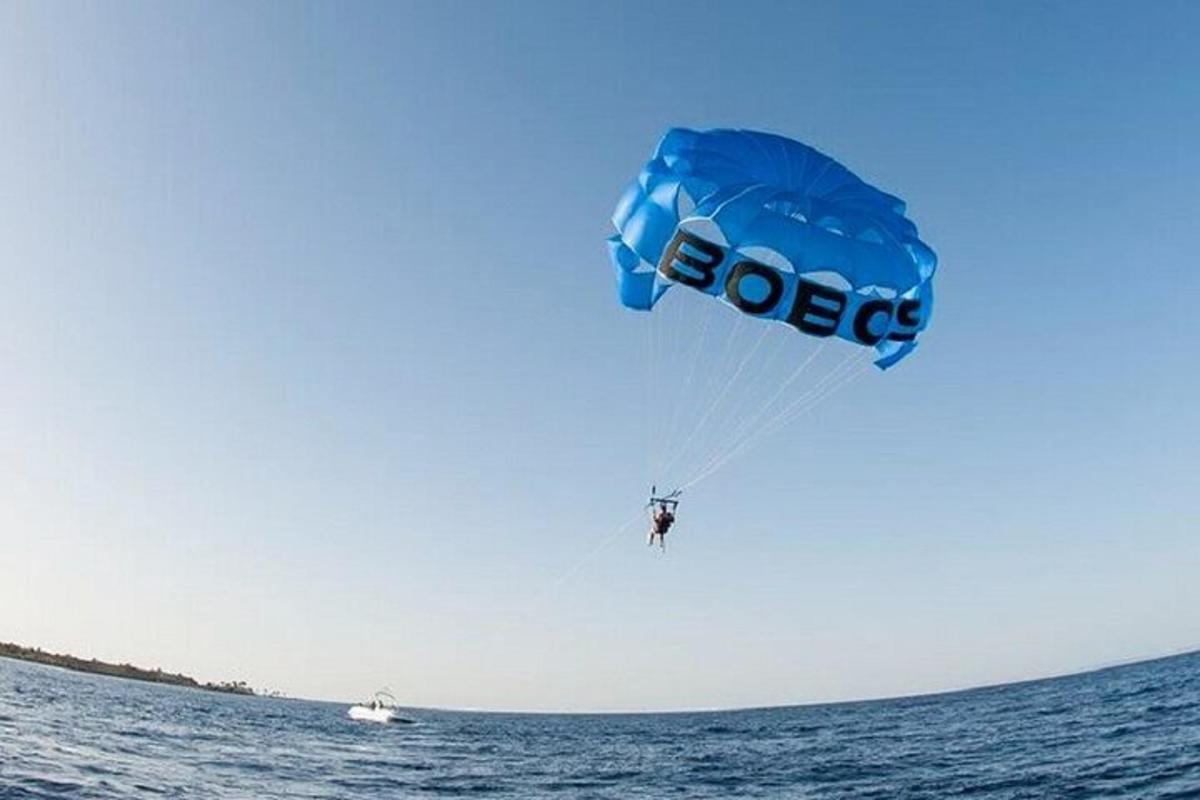 eine Person, die mit einem blauen Fallschirm im Meer Parasailing macht