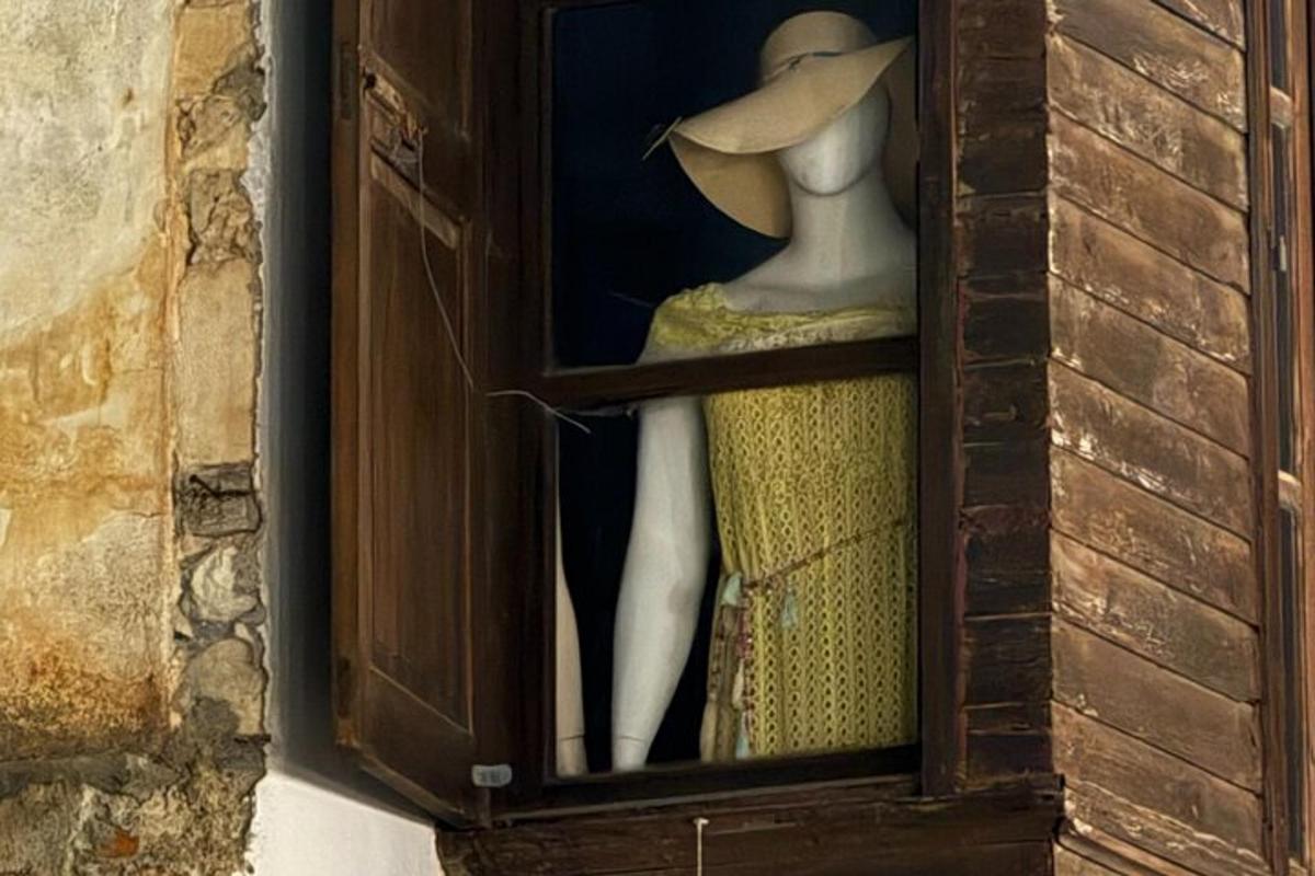 un manichino con un vestito e un cappello in una vetrina