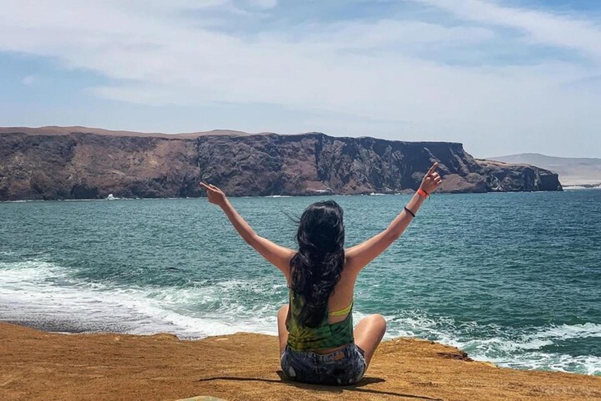 a woman sitting on the beach with her hands in the air