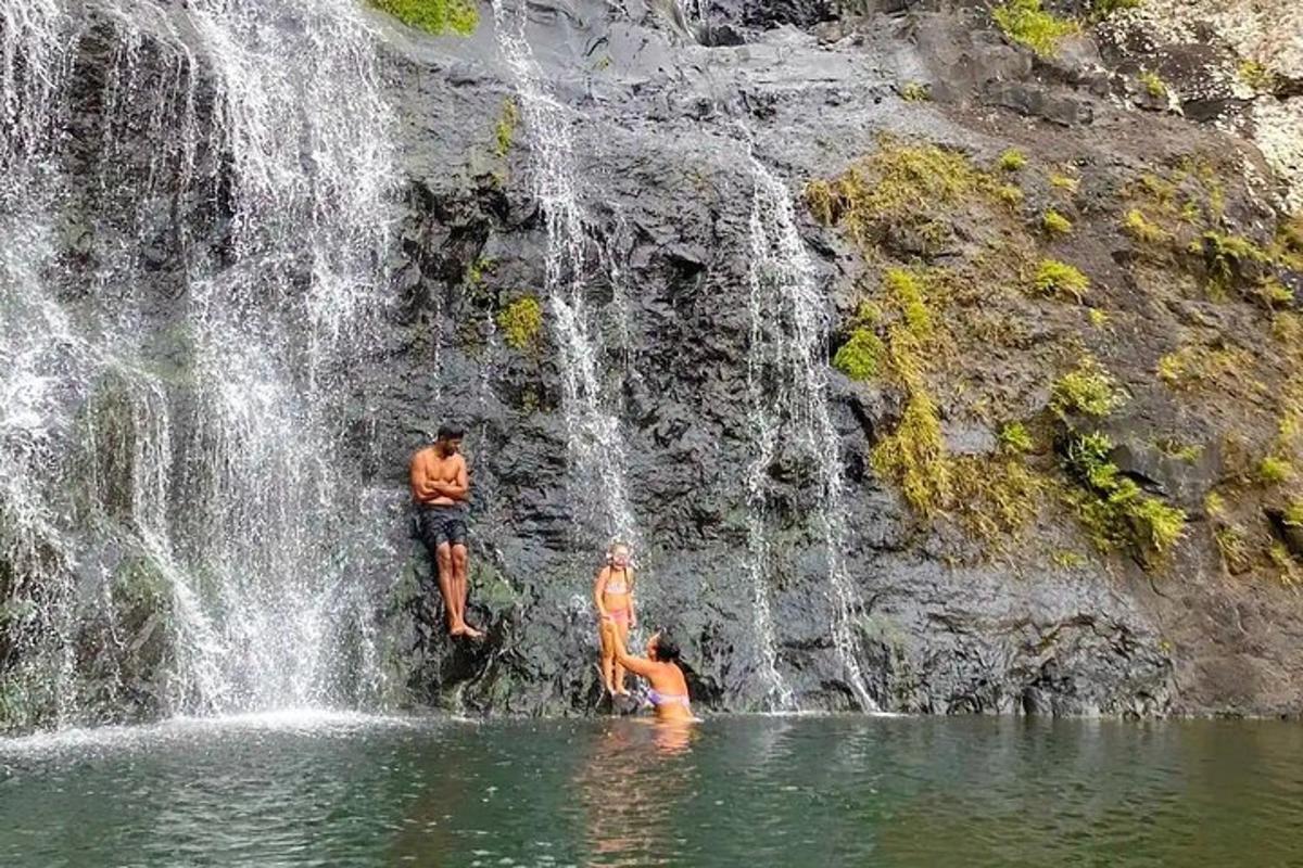 three people standing in the water under a waterfall