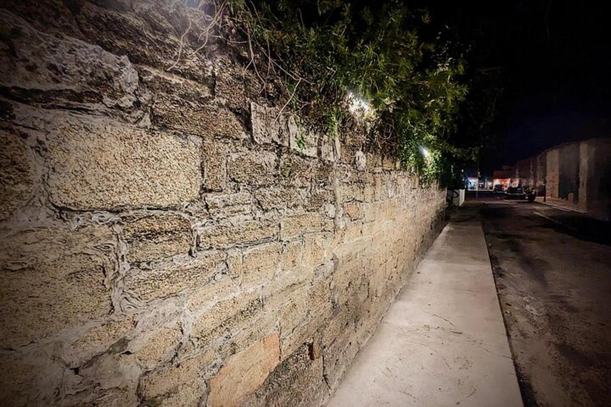 ένας πέτρινος τοίχος δίπλα σε έναν δρόμο τη νύχτα