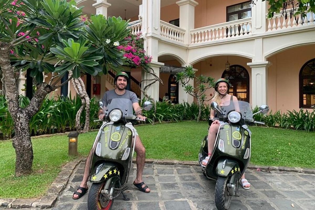 un uomo e una donna seduti su scooter davanti a una casa