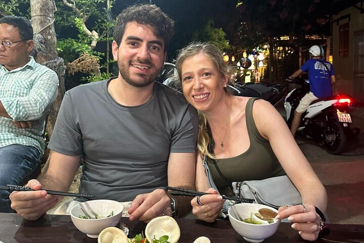 um homem e uma mulher sentados à mesa com tigelas de comida