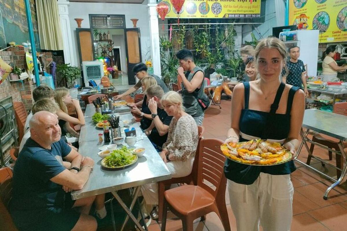 una donna che tiene in mano un piatto di cibo in un ristorante