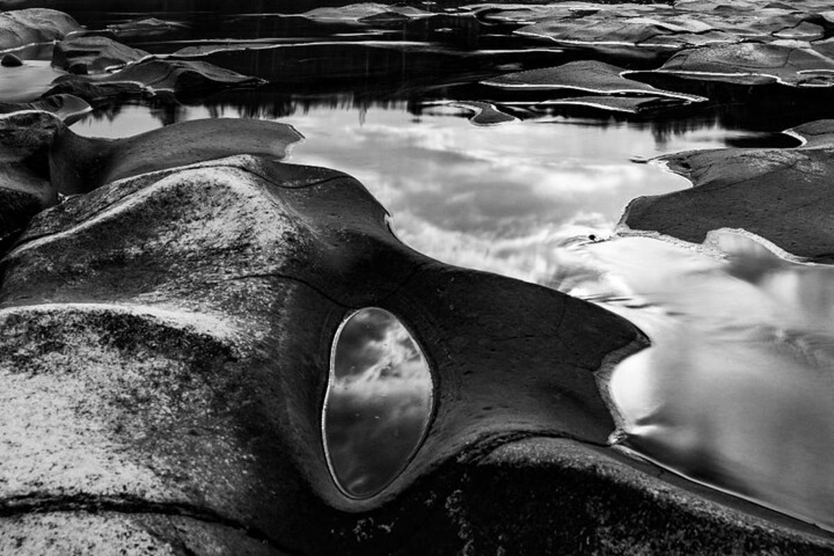 a rock with a reflection of the sky in the water