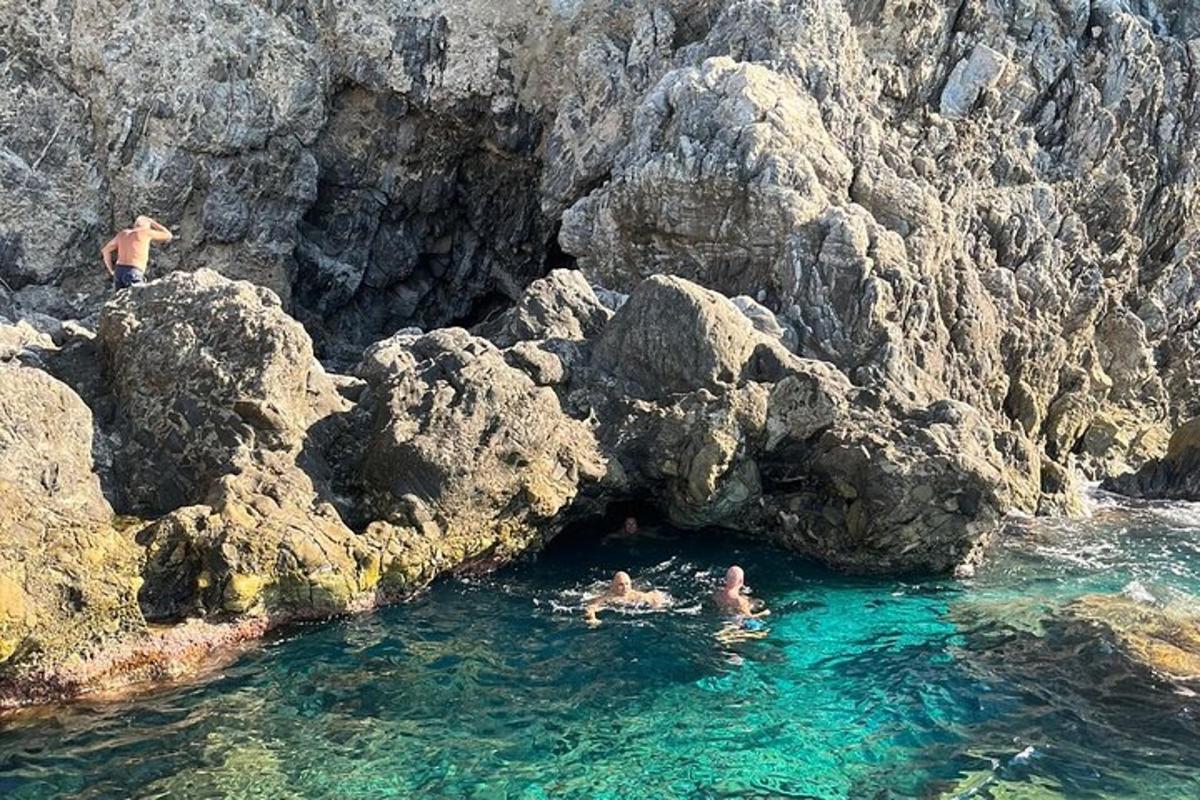dues persones nedant a l'aigua prop d'unes roques