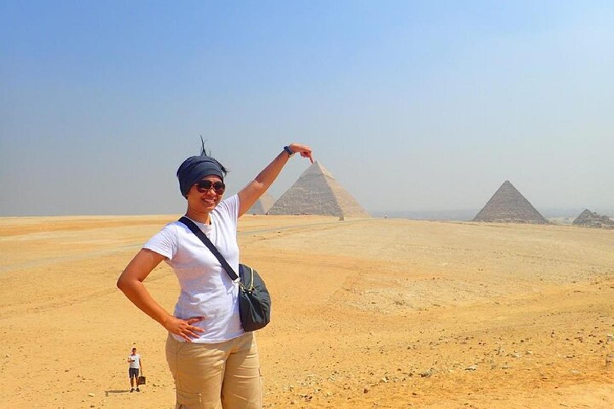 eine Frau steht in der Wüste mit Pyramiden im Hintergrund