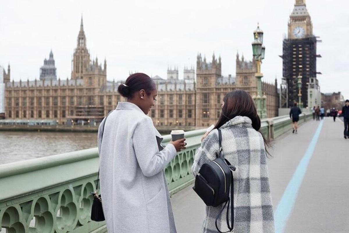 duas mulheres em pé em uma ponte olhando para um celular