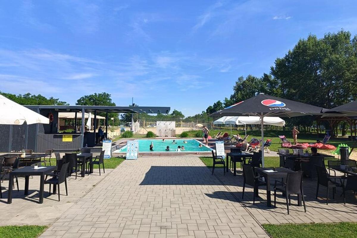 a pool with tables and umbrellas and a group of people