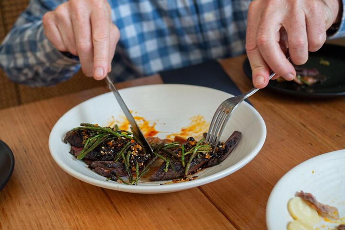 人がフォークとナイフを使って皿の上の食べ物を食べている