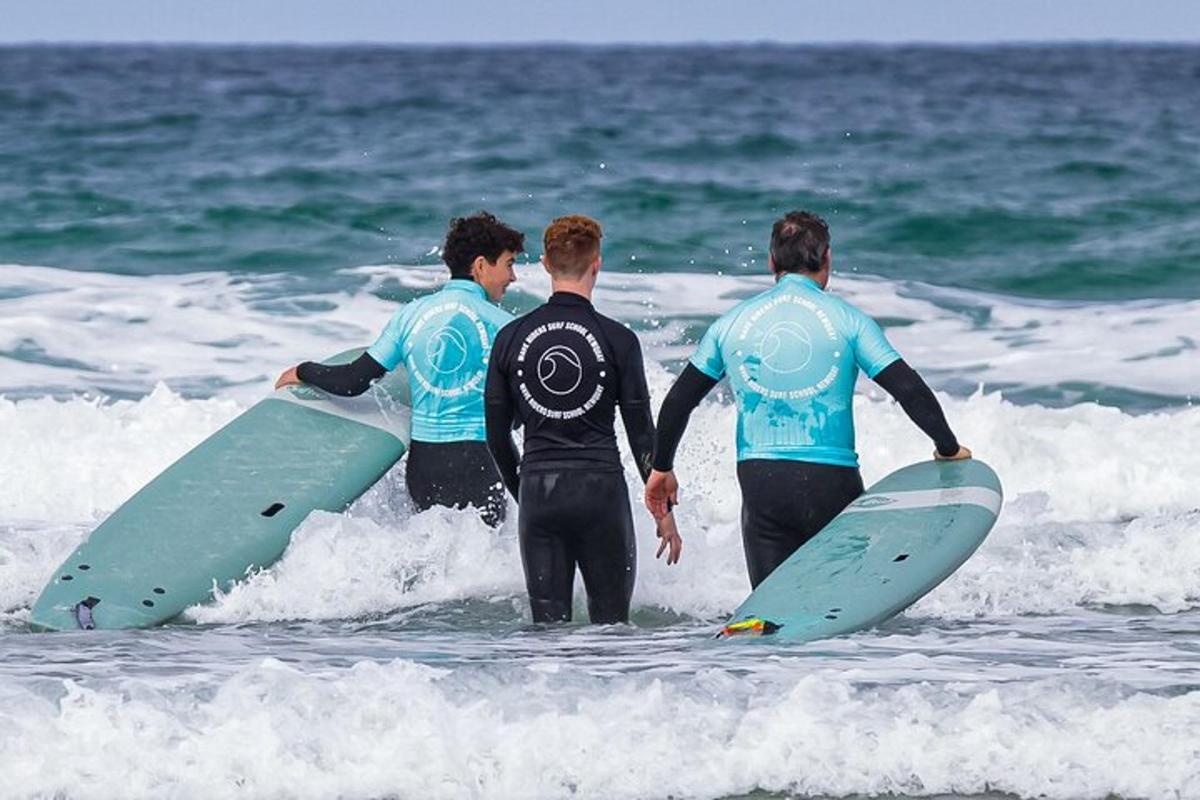 drie mannen staan in de oceaan met hun surfplanken in hun handen