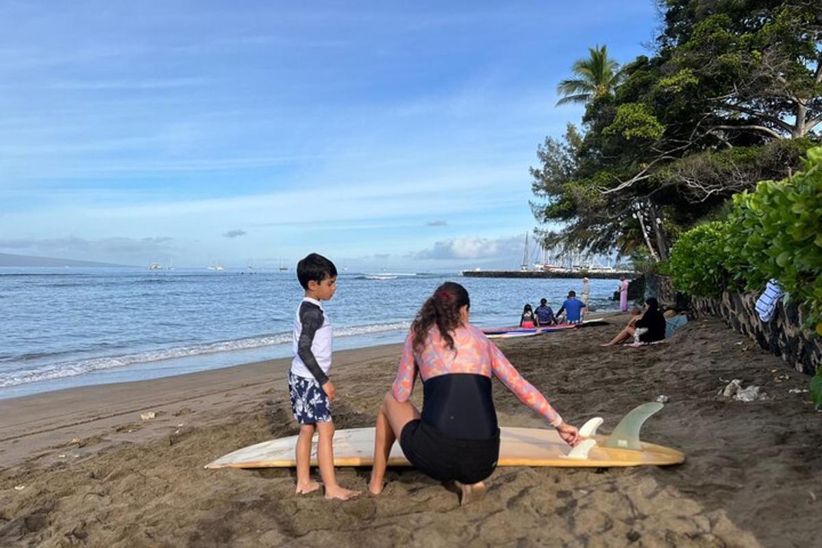 a woman and a boy sitting on a surfboard on the beach